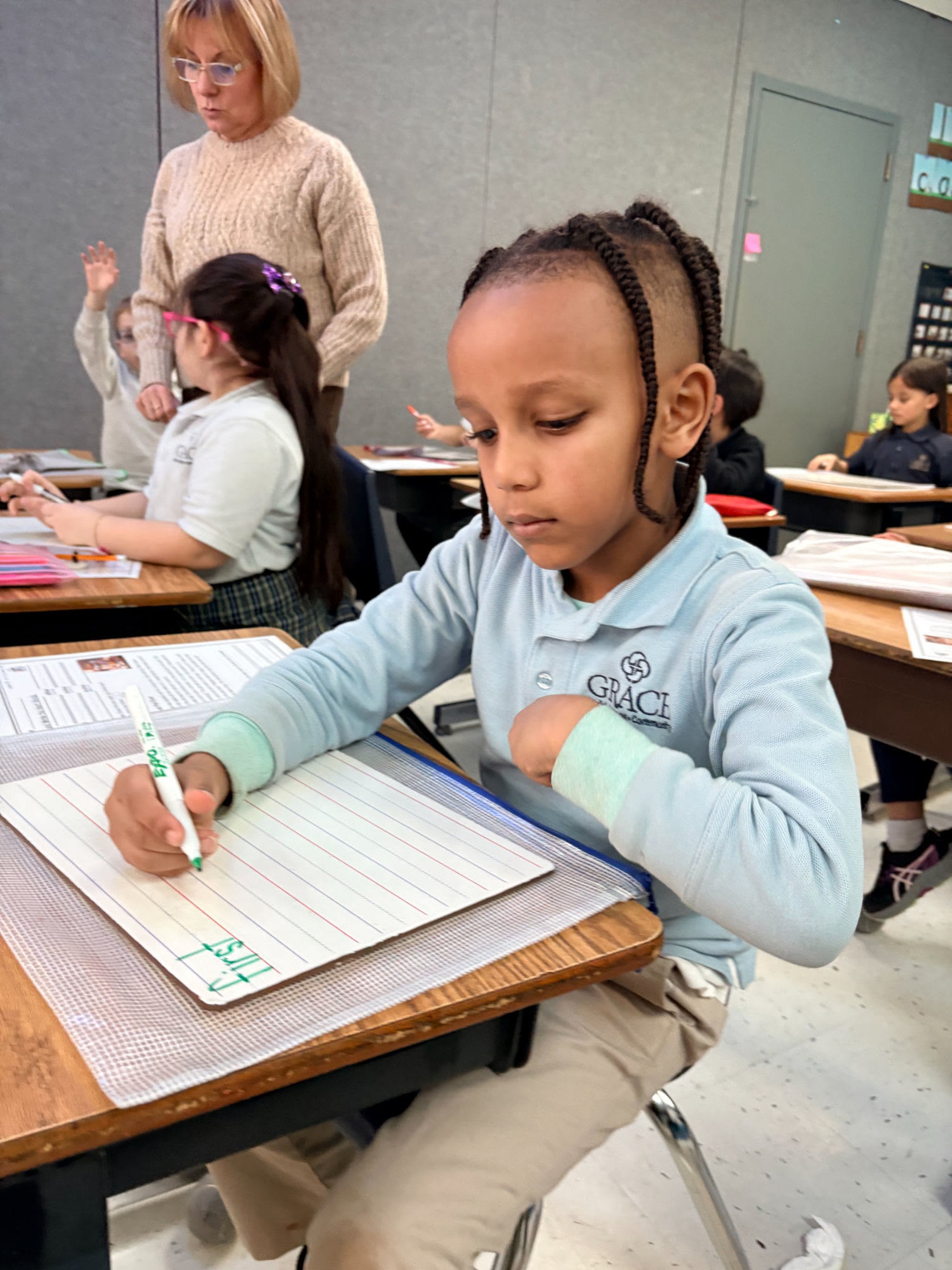 A Grace Christian Academy elementary student writing at his desk