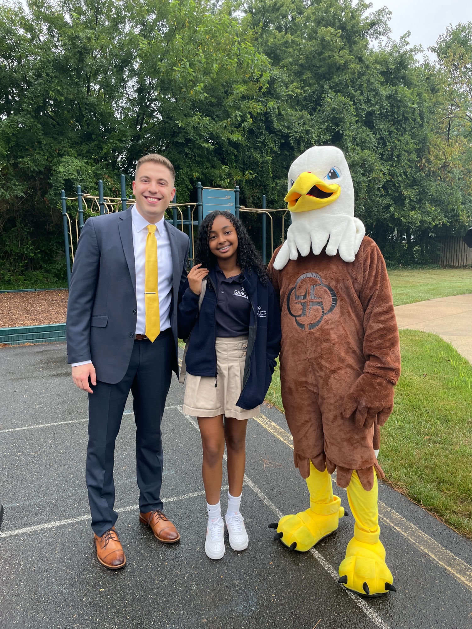 A Grace Christian Academy middle school student with a teacher and the Eagle mascot